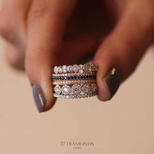 a woman's hand holding two wedding bands with diamonds on them and the words, 7