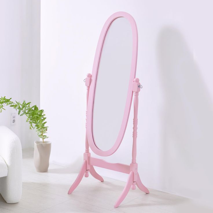 a pink vanity mirror sitting on top of a wooden stand next to a potted plant