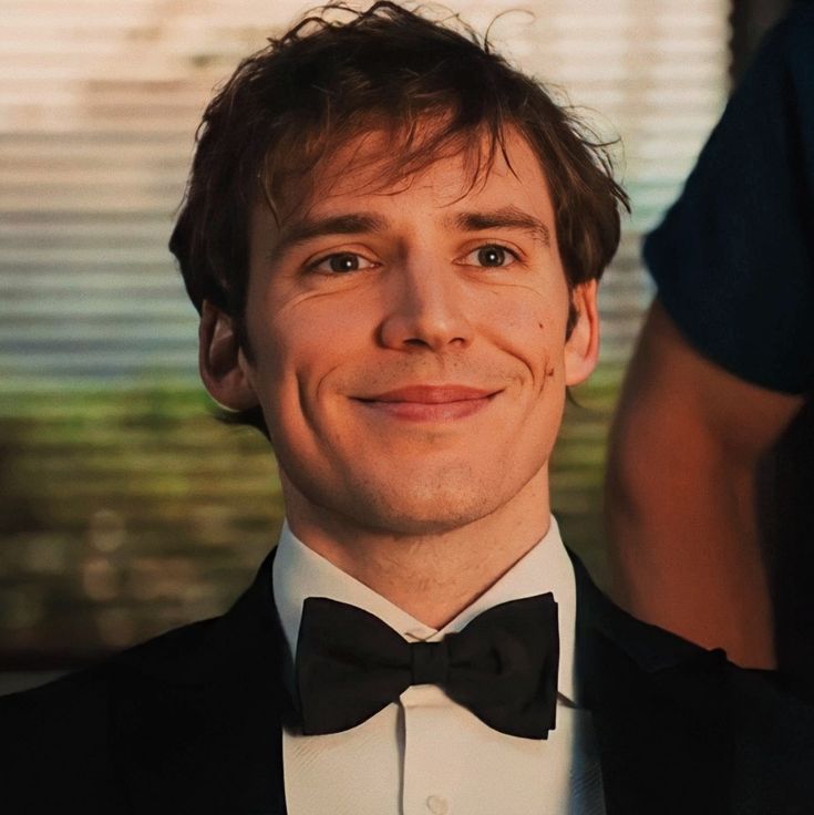 a man in a tuxedo smiles at the camera while wearing a bow tie