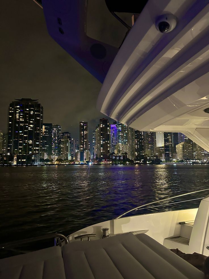 the city skyline is lit up at night as seen from a boat