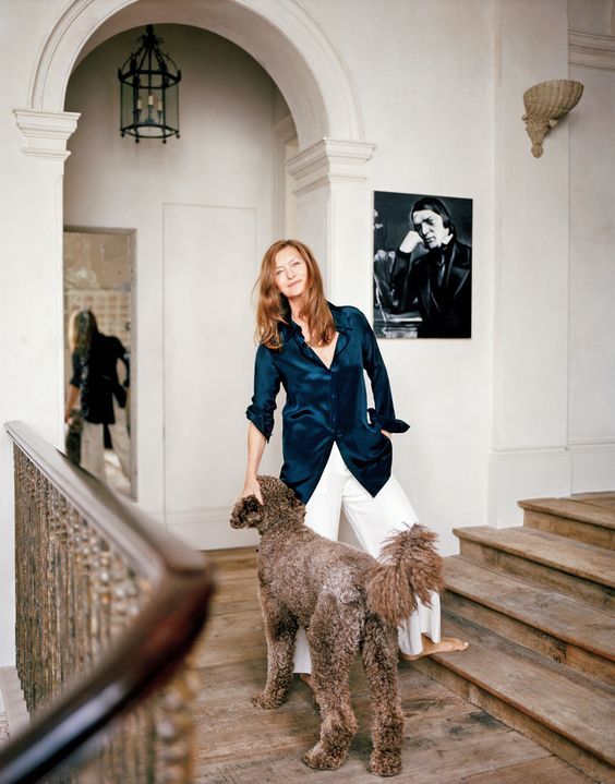 a woman standing next to a brown poodle on top of a wooden stair case