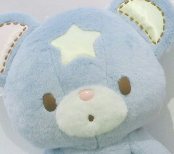 a blue teddy bear with a star on it's head and ears, sitting against a white background