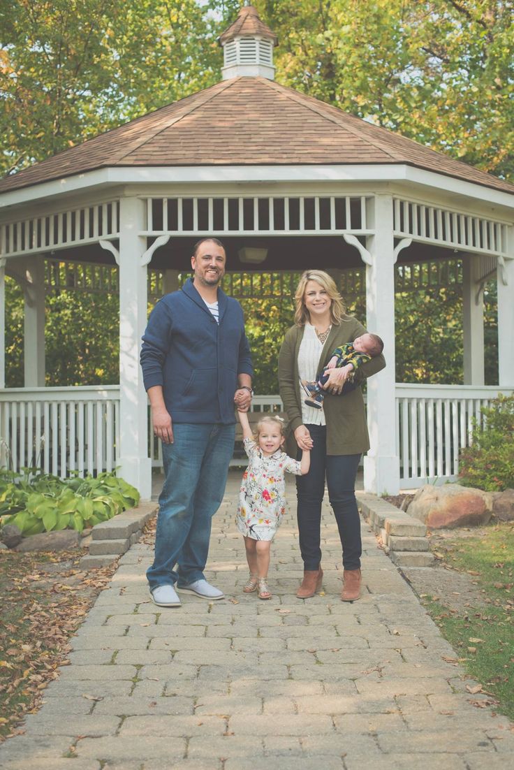 a man, woman and child standing in front of a gazebo