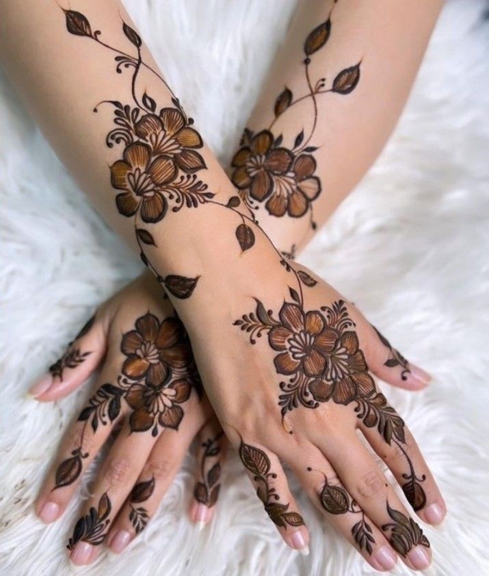 two hands with henna tattoos on them, one is brown and the other is black