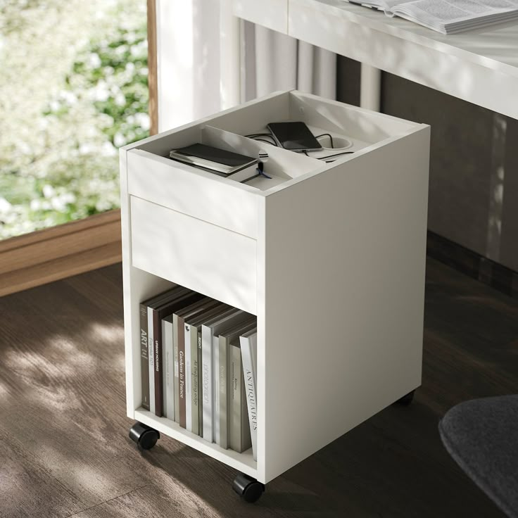 a white book shelf with books on it in front of a window and wooden floor