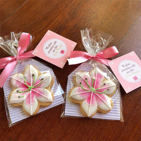 three decorated cookies in plastic bags with pink bows on the top and tags attached to them