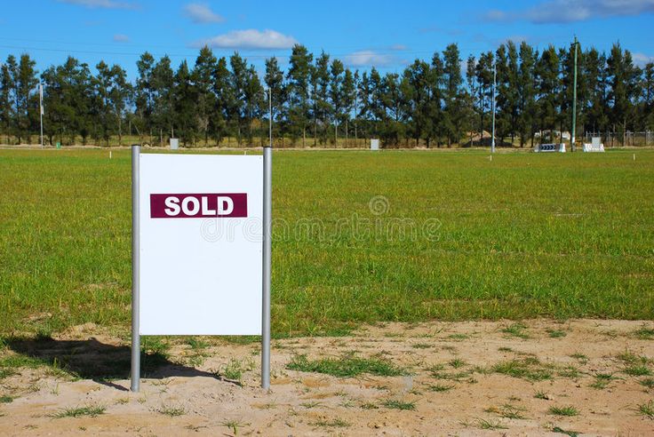 a sold sign in the middle of a grassy field with trees in the background stock photos