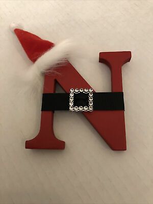 the letter k is decorated with santa's hat and black ribbon on top of it