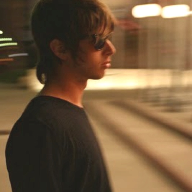 a man standing in front of a train track with his head turned to the side