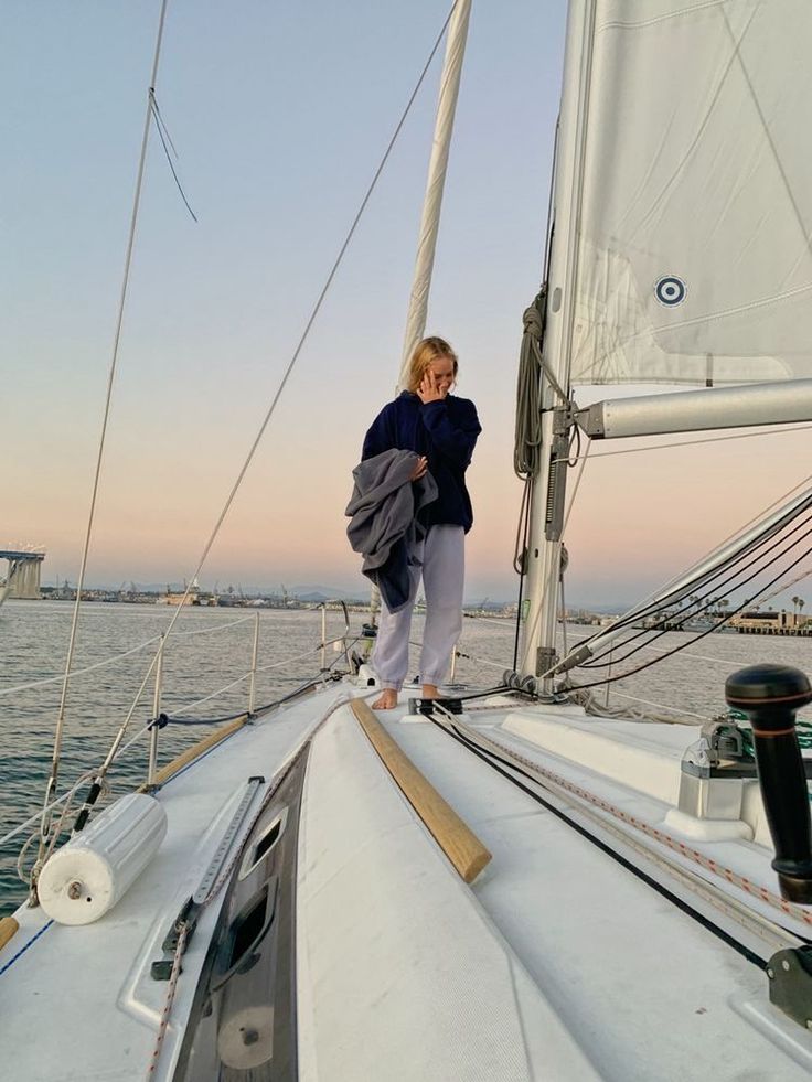 a woman standing on the deck of a sailboat