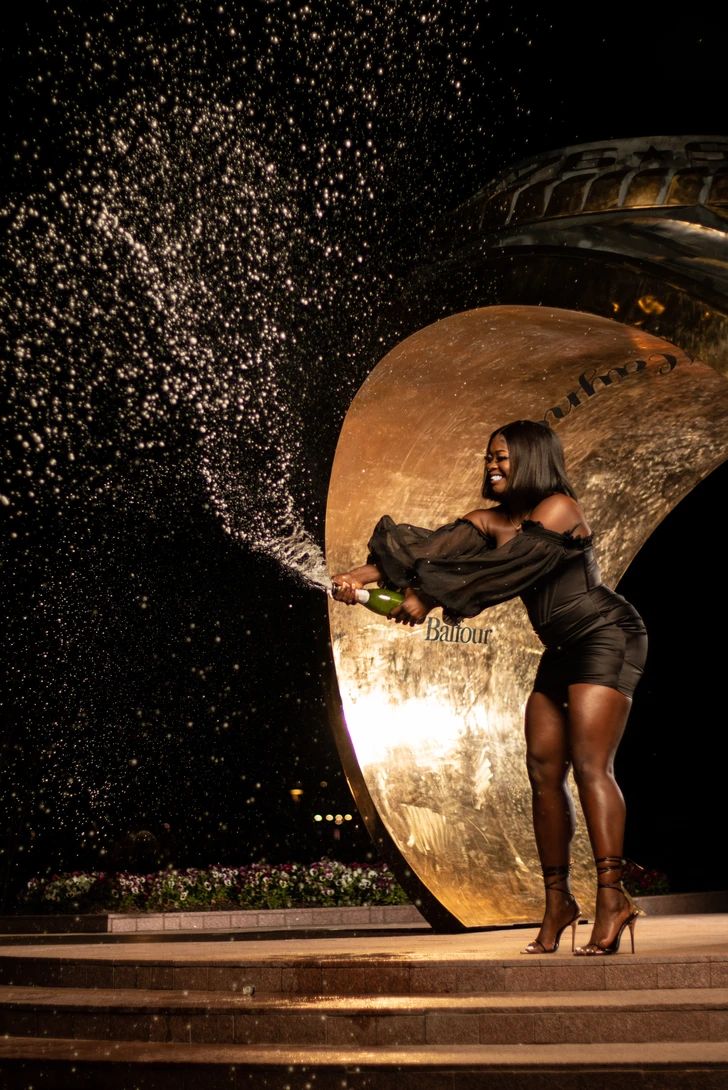 a woman is standing on some steps and spraying champagne