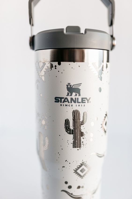 a stainless steel tumbler with cactus designs on the front and side, sitting on a white surface