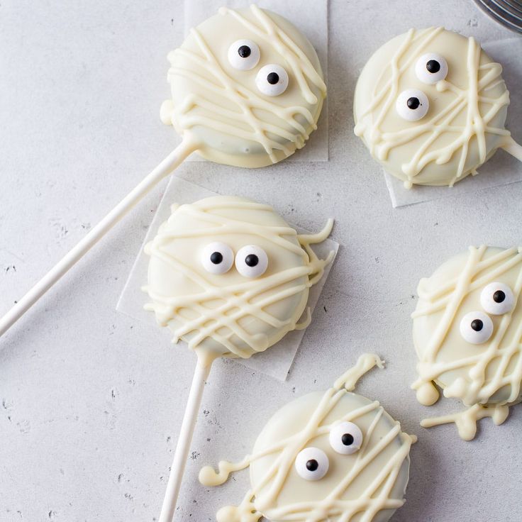 four decorated cookies with googly eyes and white icing