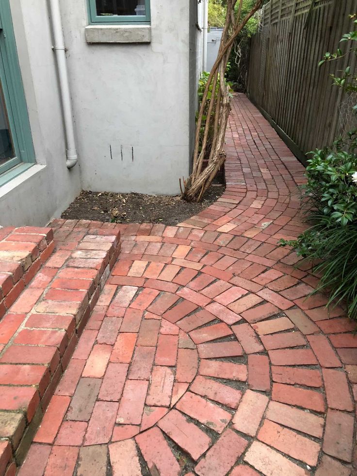 a red brick walkway next to a white house