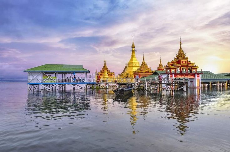 boats are docked in the water next to buildings with golden spires on them at sunset