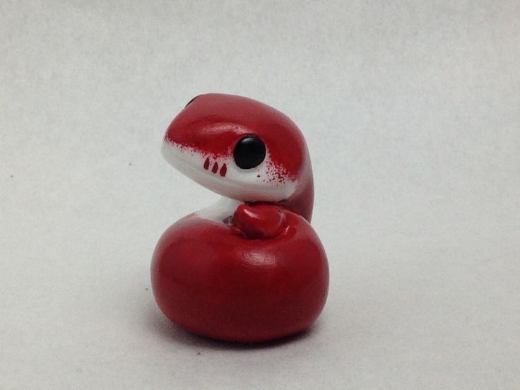 a red and white toy snake sitting on top of a white table next to a black eye