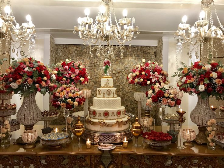 a wedding cake surrounded by vases with flowers and candles on the table in front of it