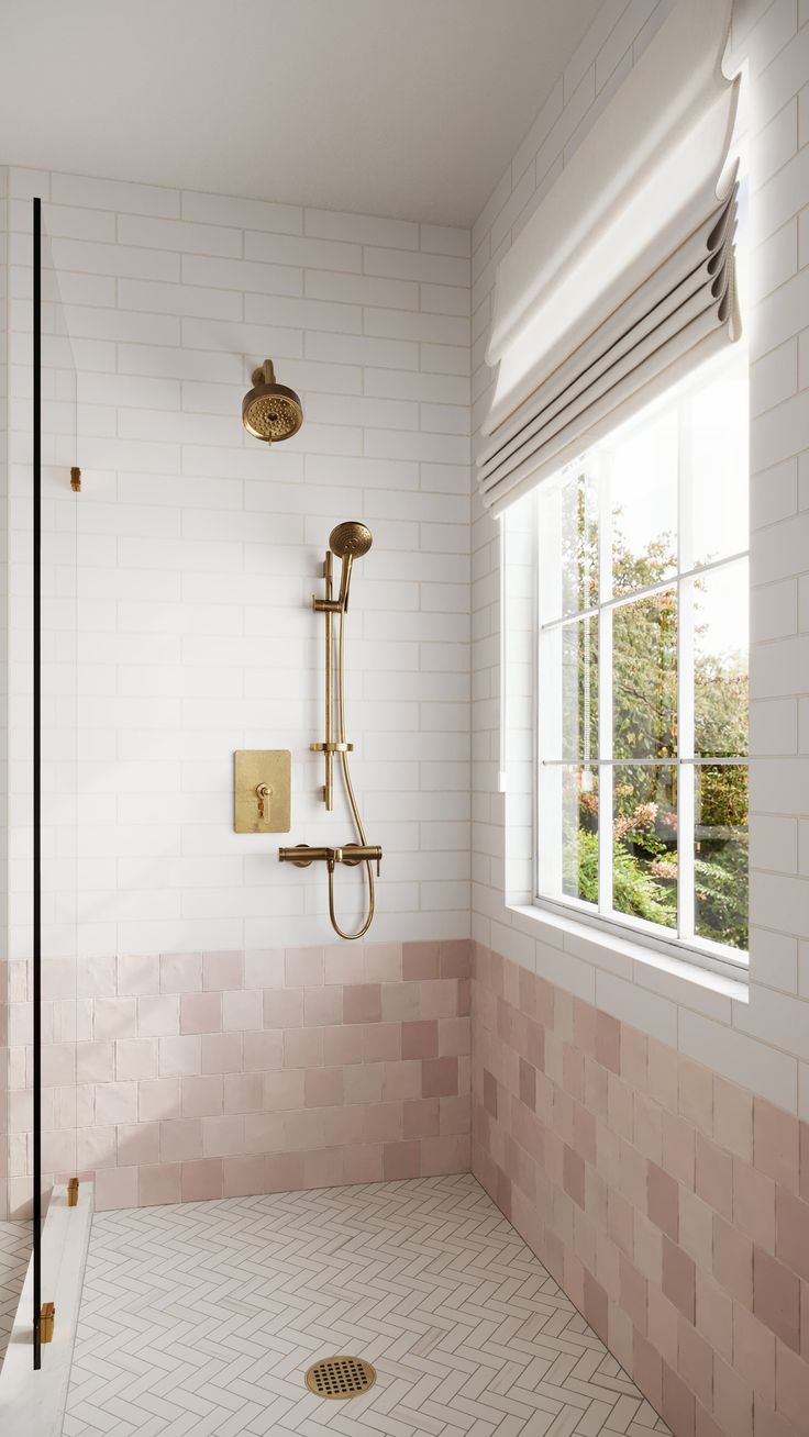 a bathroom with pink and white tiles on the walls, shower head, and window