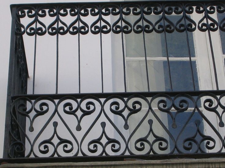 an iron balcony railing with a window in the background