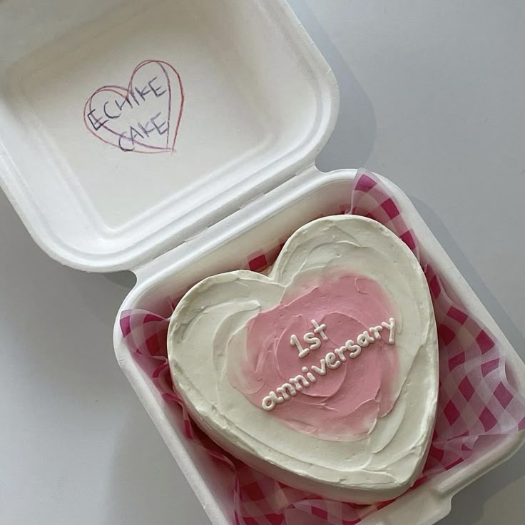 a heart shaped cake in a pink and white box with the words 1st anniversary written on it