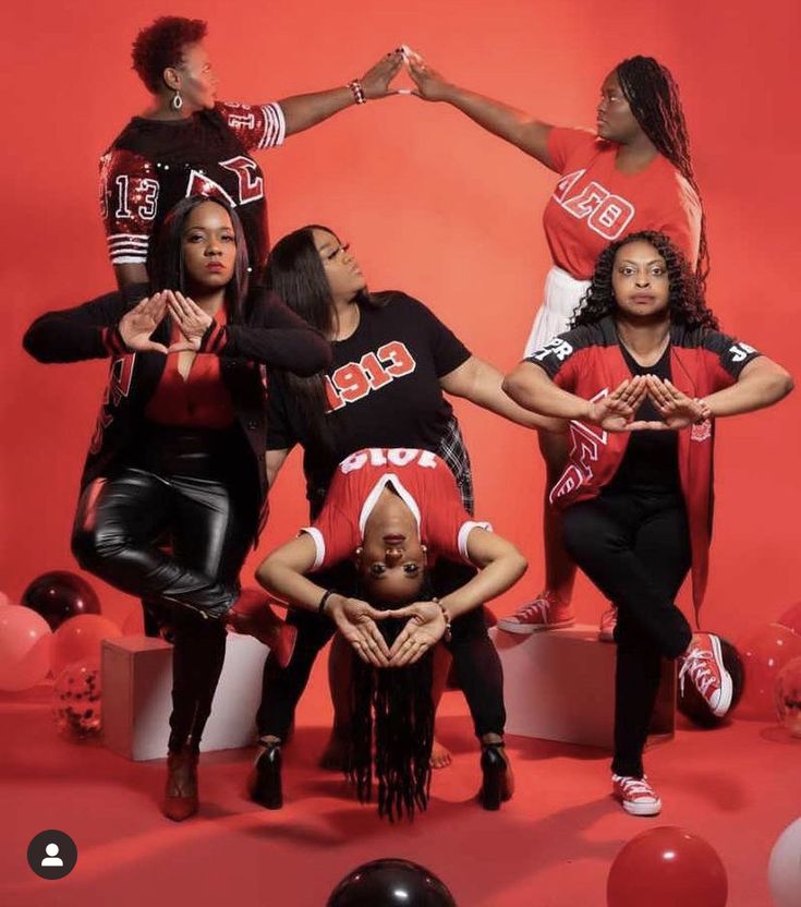 a group of women in red shirts and black pants posing for a photo with balloons