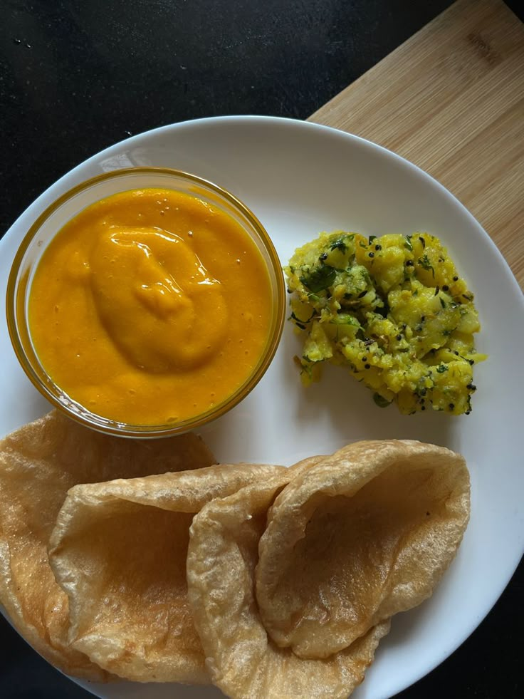 a white plate topped with food next to a bowl of sauce