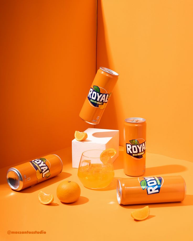 orange juice in cans and two lemons on an orange surface with the word royal printed on them