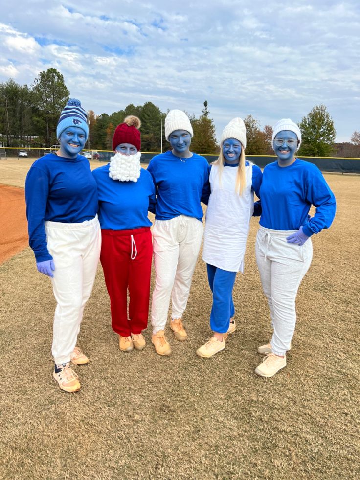 four people in blue and white costumes standing on a baseball field