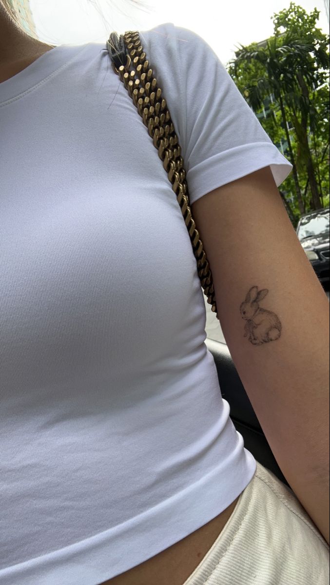 a woman with a small tattoo on her left arm and right arm behind her back