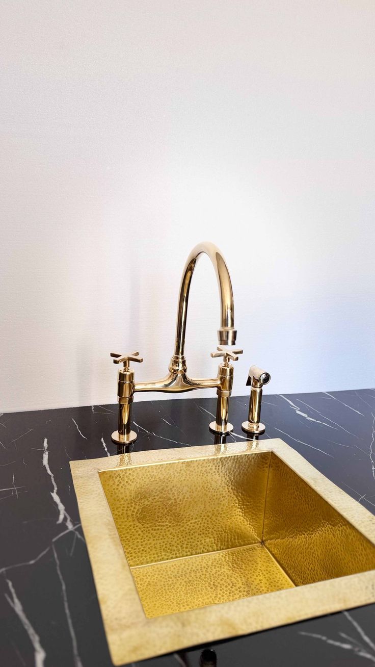 a bathroom sink with gold faucet and black marble counter top