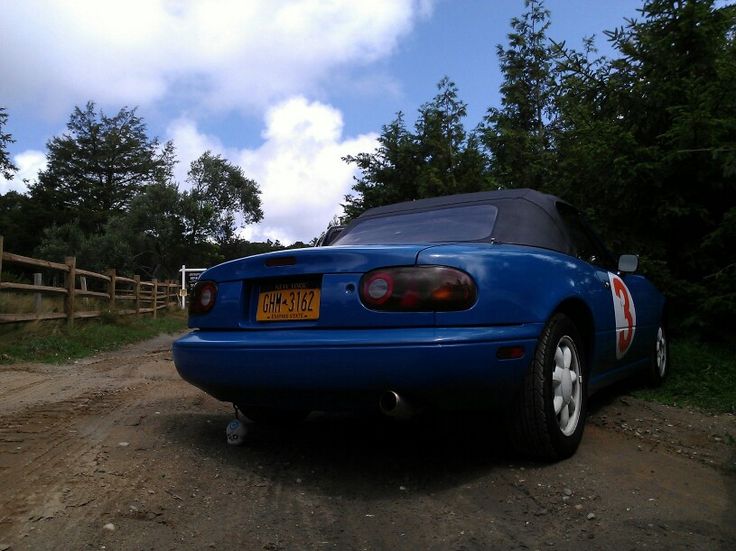 a blue sports car parked on a dirt road