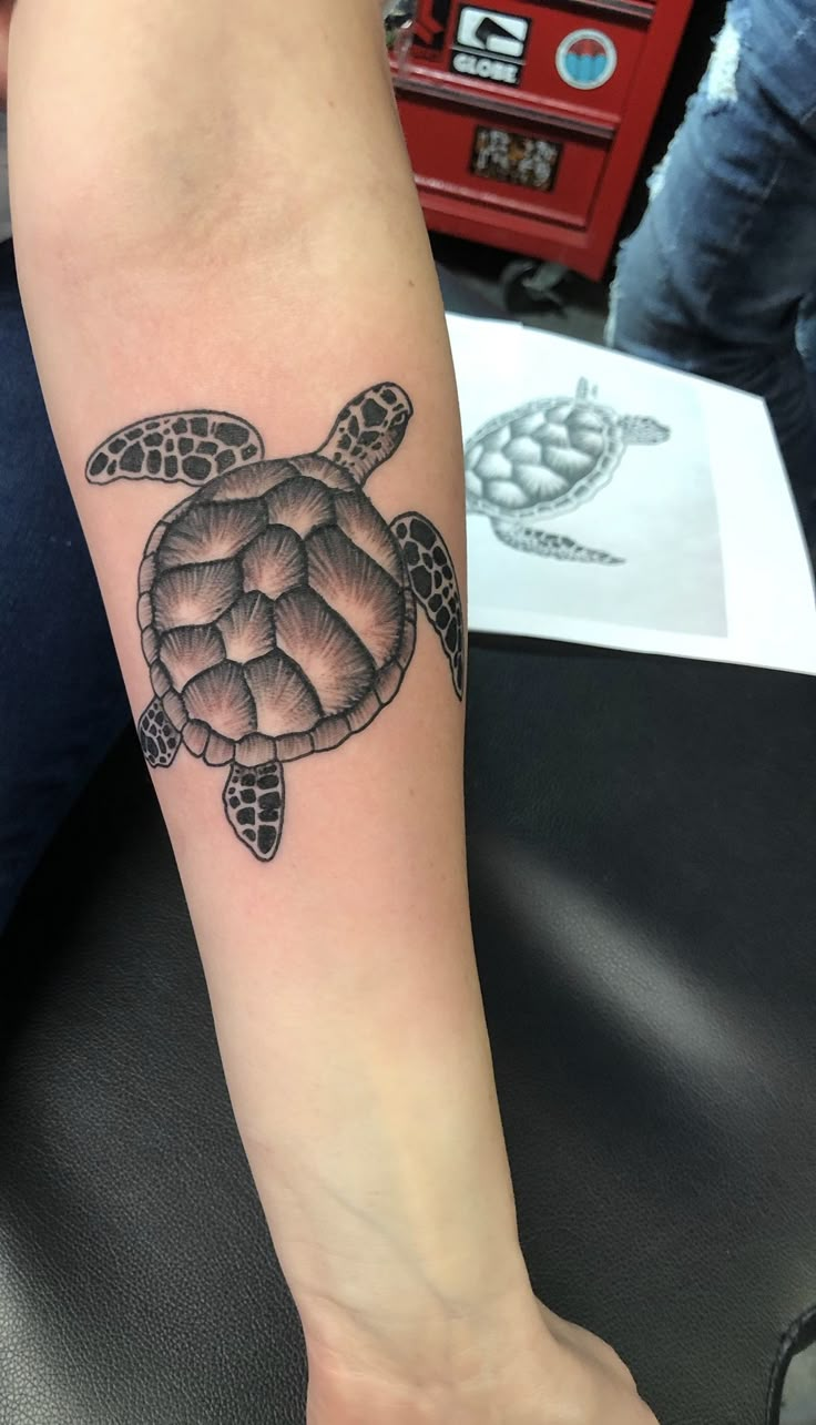 a woman's arm with a turtle tattoo on it