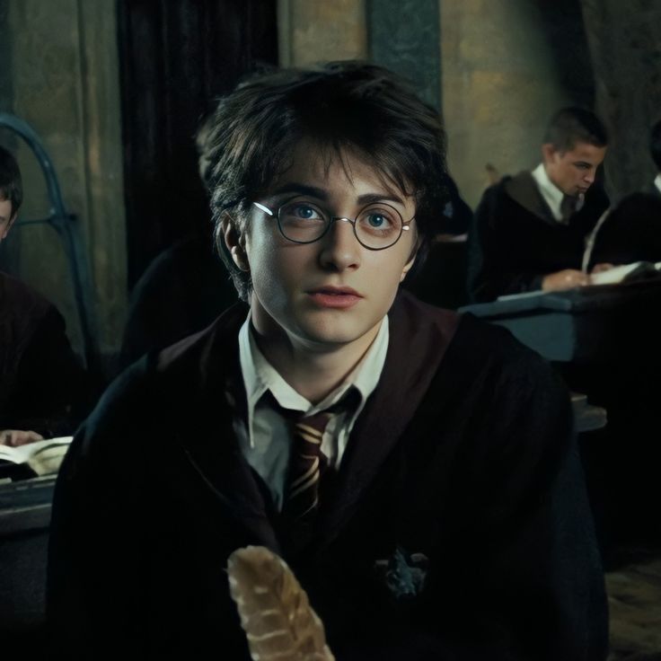 harry potter is sitting at his desk in front of the camera and looking off into the distance