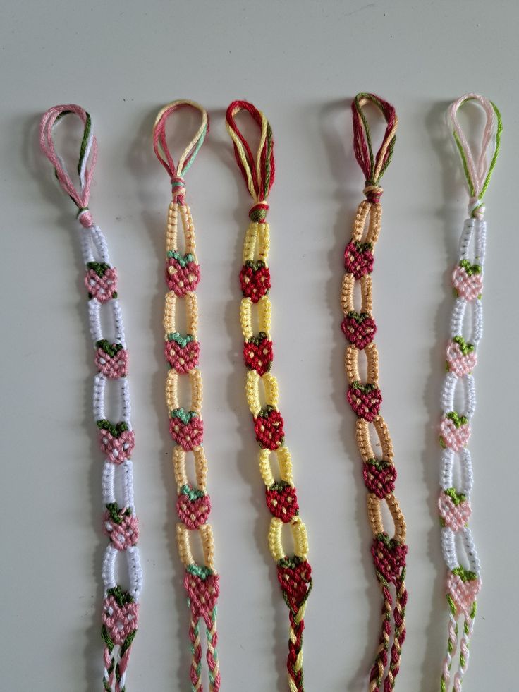 four different types of bracelets are lined up on a table together, one is white and the other is red