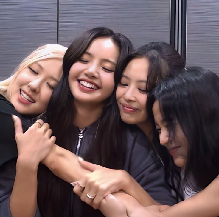 four young women are hugging and smiling together