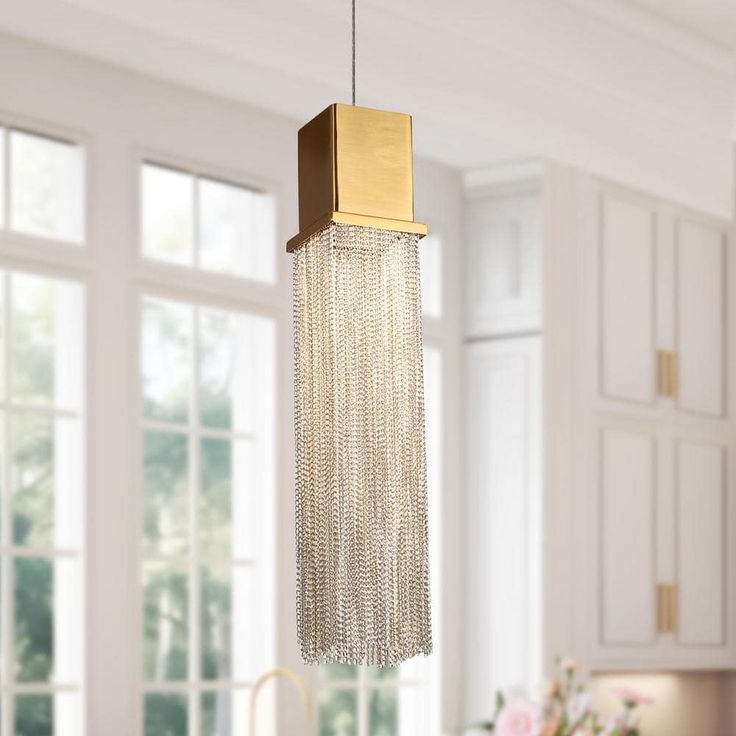 a kitchen with white cabinets and a gold colored light fixture hanging from the ceiling above it