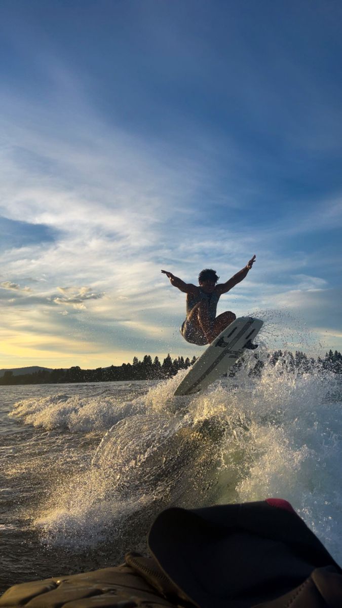 a man riding a wave on top of a surfboard in the ocean at sunset