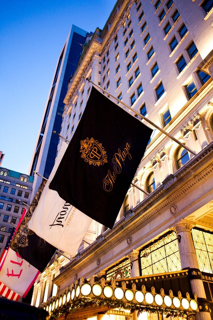 the hotel is lit up at night in front of it's large building and flags