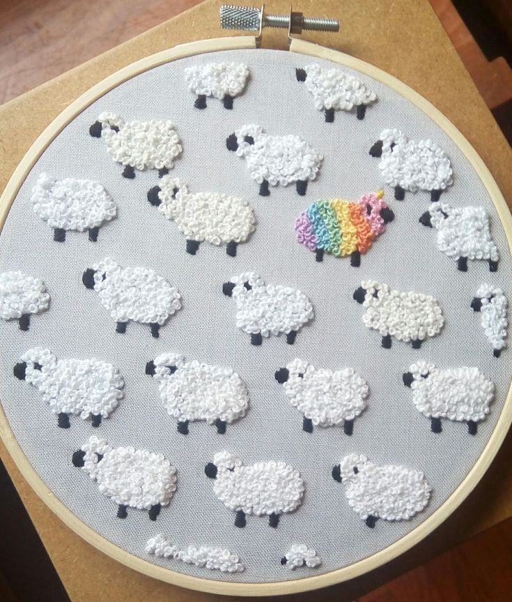 a cross stitch pattern with sheep in the middle and a rainbow pin on one side