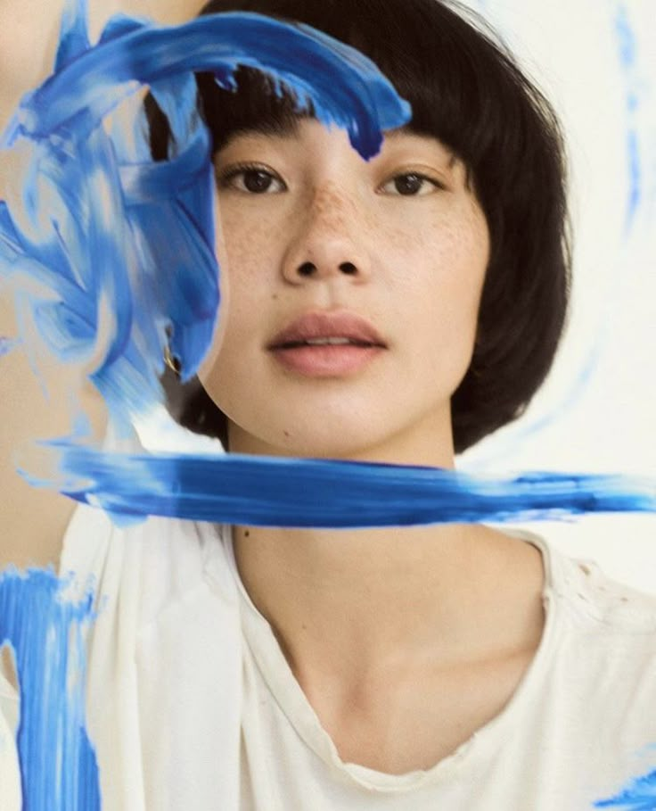 a woman with black hair and blue paint on her face