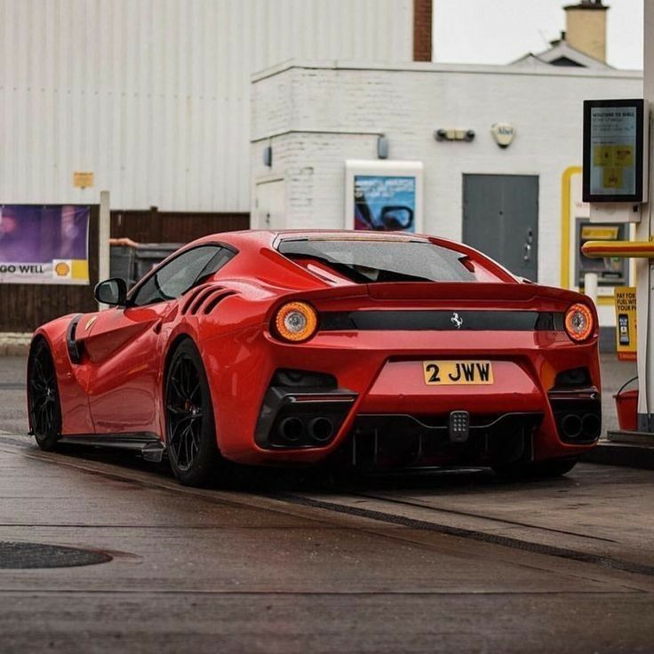 a red sports car parked in front of a gas station