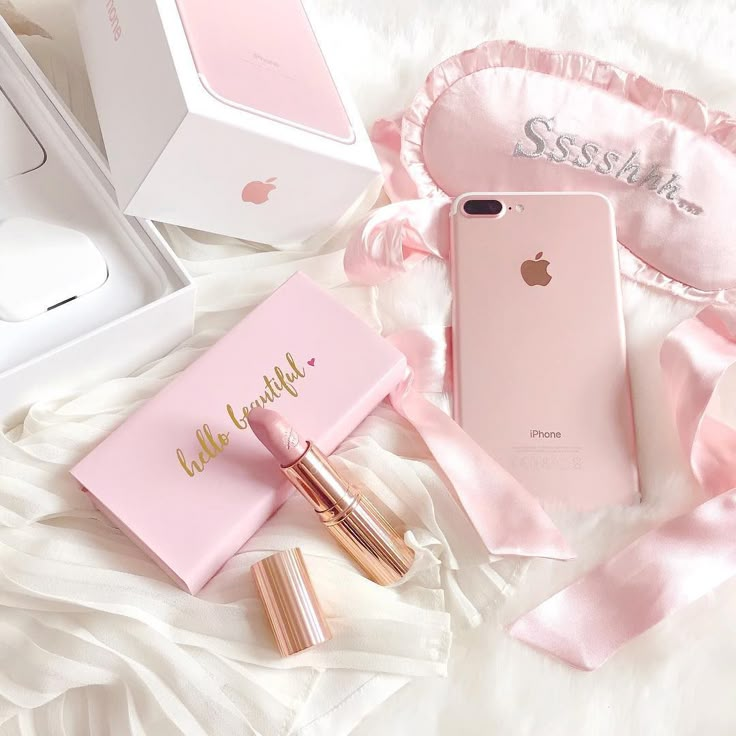 the contents of an iphone case and lipstick are laid out on a white bed with pink satin