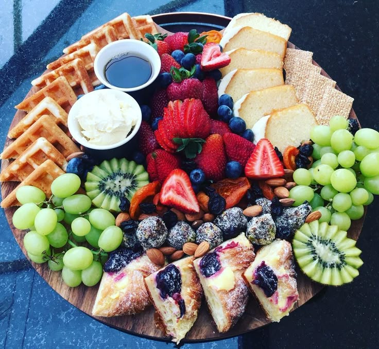 a wooden platter filled with fruit and waffles