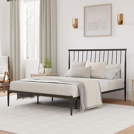 a bedroom with white walls and wood flooring has a metal bed frame in the middle