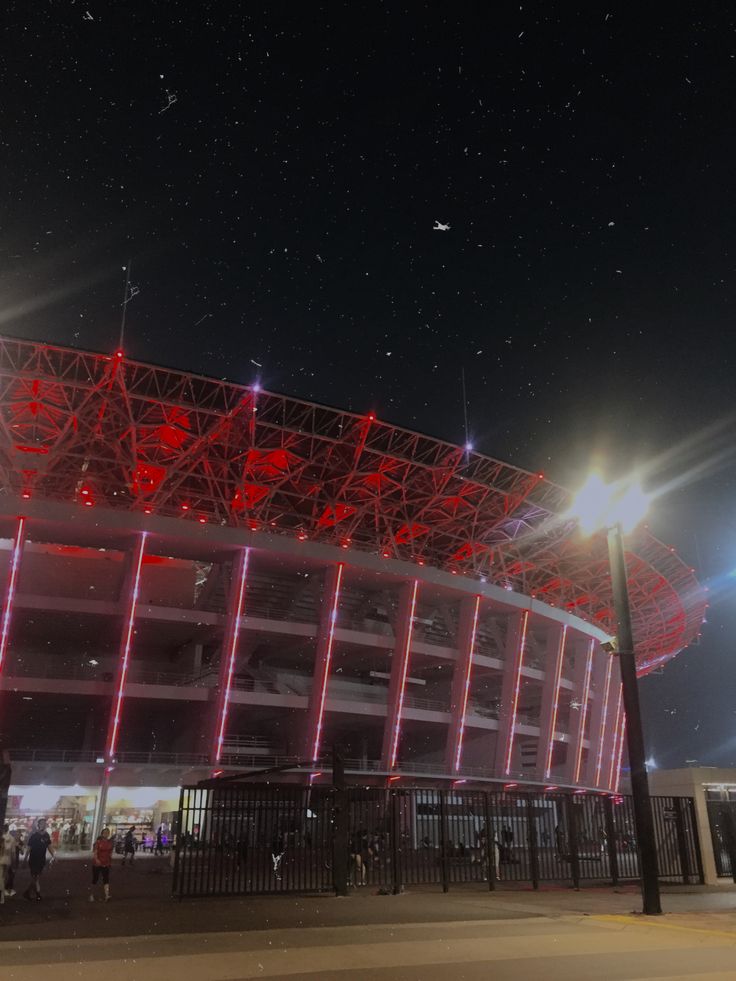 an illuminated stadium at night with people walking around