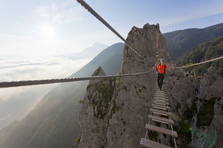 a man is walking across a rope bridge