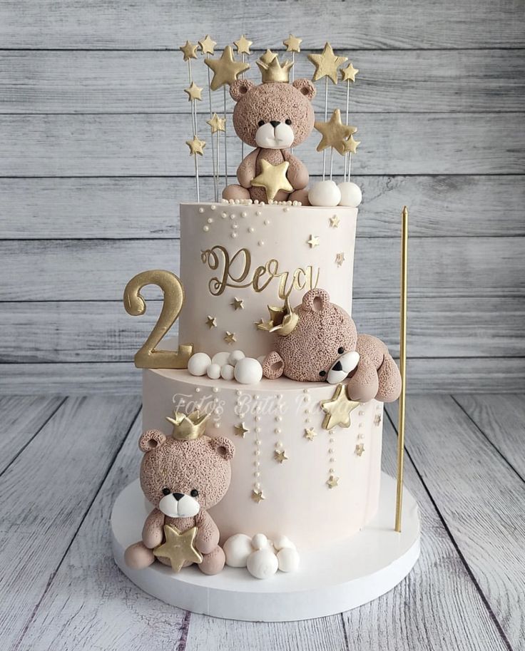 a two tiered cake with teddy bears on top and stars around the edges, sitting on a wooden table