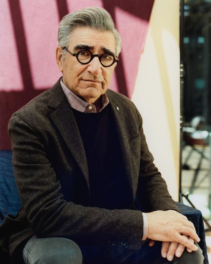 an older man wearing glasses sitting on a chair