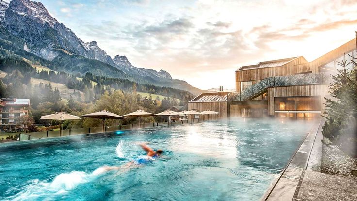 a person swimming in a large pool with mountains in the backgrouds behind them