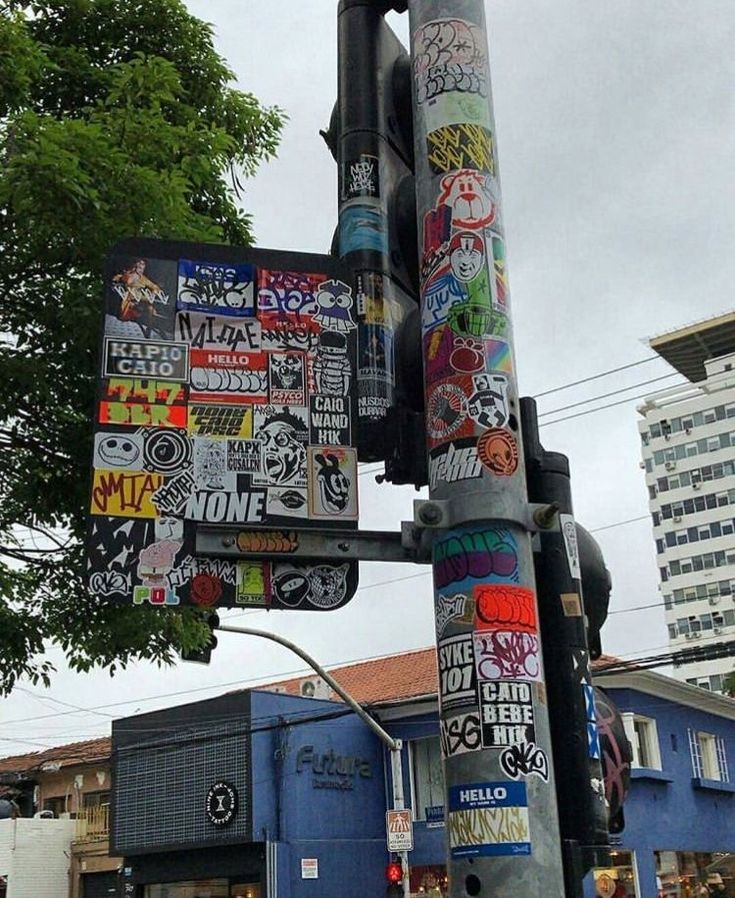 a traffic light covered in lots of stickers on it's side next to a street